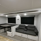 U-Shaped Dinette Next to Sofa Shown in Greystone Décor.
