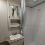 Bathroom with Mirrored Medicine Cabinet Overhead Single Bowl Vanity. Shower with Curtain and Skylight Above.
